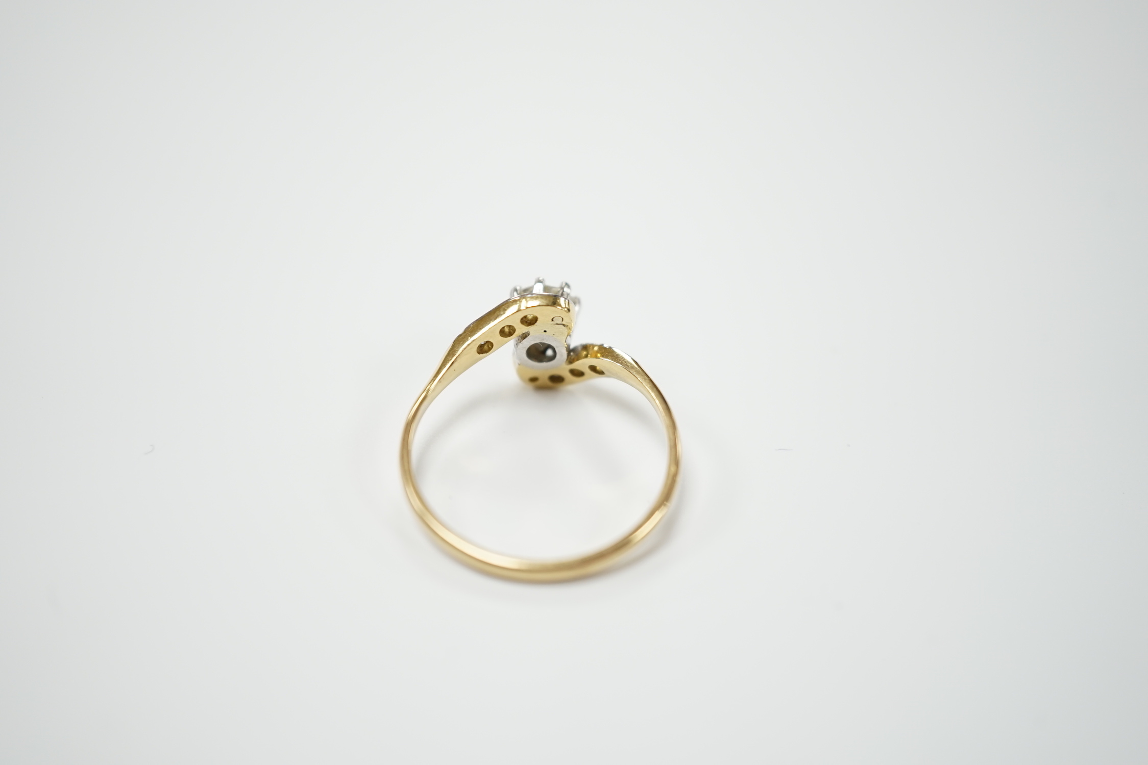 An 18ct, plat and single stone diamond set ring, with diamond chip set crossover shoulders, size P/Q, gross weight 3.1 grams.